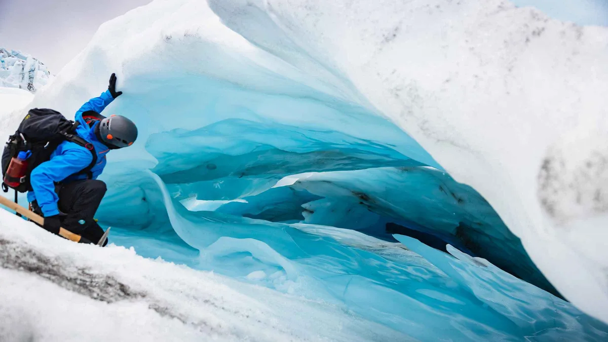 Hikers roped along a ridge of blue ice below the Falljökull icefall on a Skaftafell glacier hike in Vatnajökull National Park, Iceland